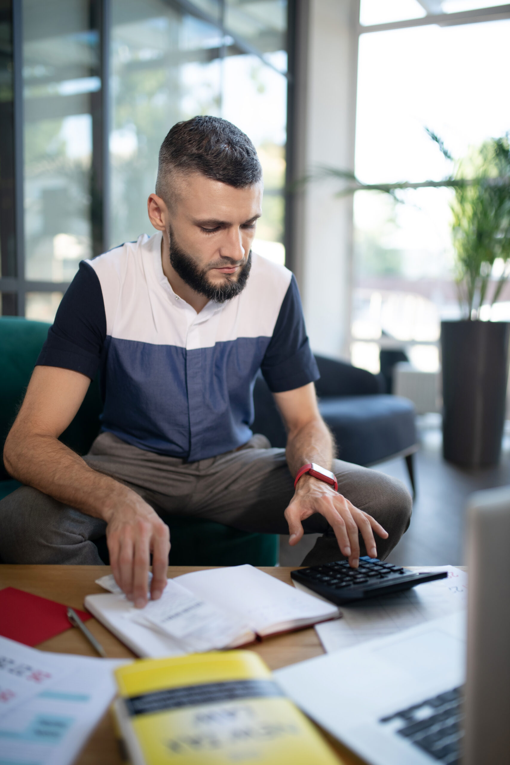 Involved in calculations. Young bearded businessman feeling involved in calculations and accounting